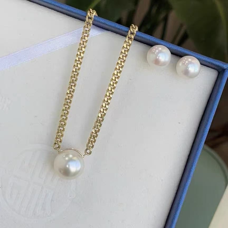 A white pearl pendant on a gold-coloured chain and a pair of pearl earrings, from M&T Jewelry